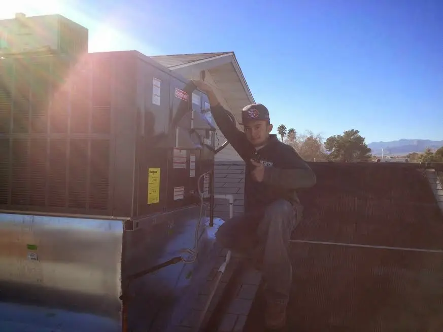 HVAC technician performing Air Duct Repair on a rooftop unit in Holly Springs